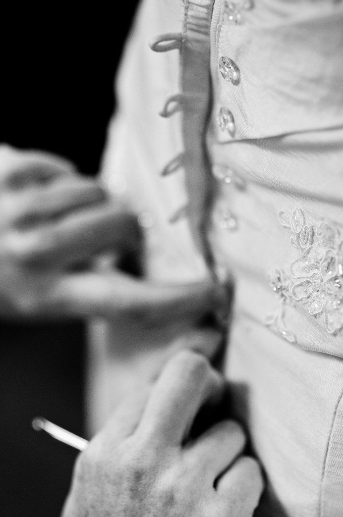 Crochet hook to button up wedding dress Bride getting dressed