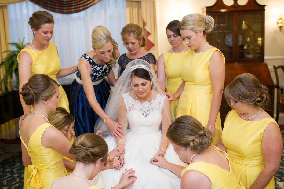 Bride praying with bridesmaids before ceremony